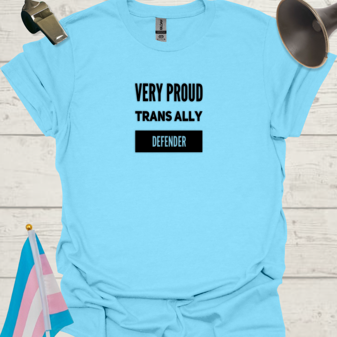 Light blue t-shirt with 'VERY PROUD TRANS ALLY DEFENDER' text on a wooden surface with a transgender flag and megaphone.