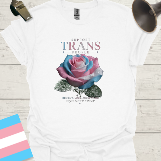 White t-shirt with a colorful rose graphic and text on a wooden surface